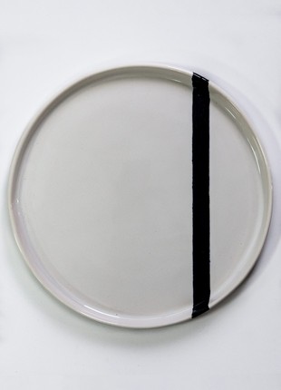 Hand-made dish with flat sides of white color with black stripe
